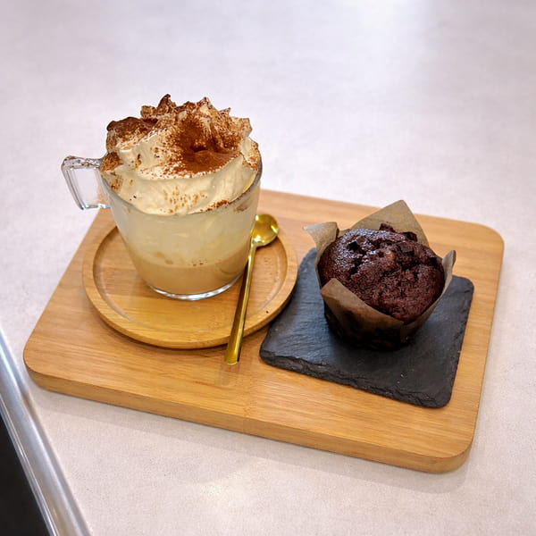 Caffè macchiato con panna, cacao e muffin al cioccolato