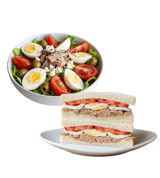 Un'insalata mista con pomodori freschi, uova sode, tonno e olive e un tramezzino doppio imbottito con tonno, uova sode e pomodoro fresco, appoggiati su piatti bianchi da portata