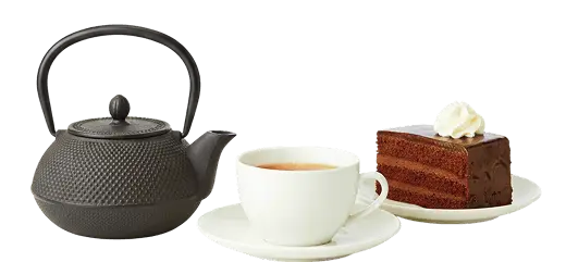Teiere cinese in ghisa con tazza di te fumante e una fetta di torta sacher invitante